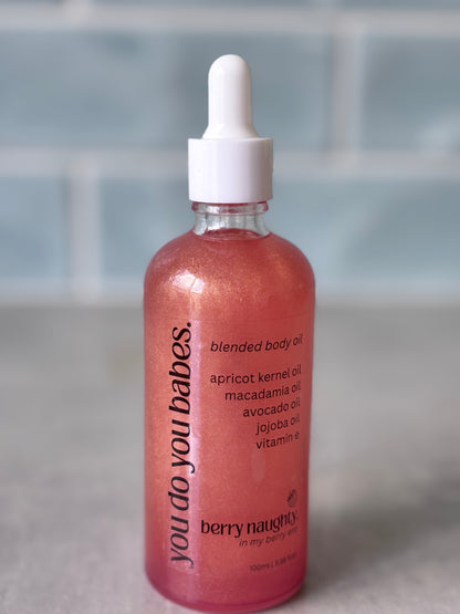 Bottle of 'you do you babes' Berry naughty blended body oil on a neutral background