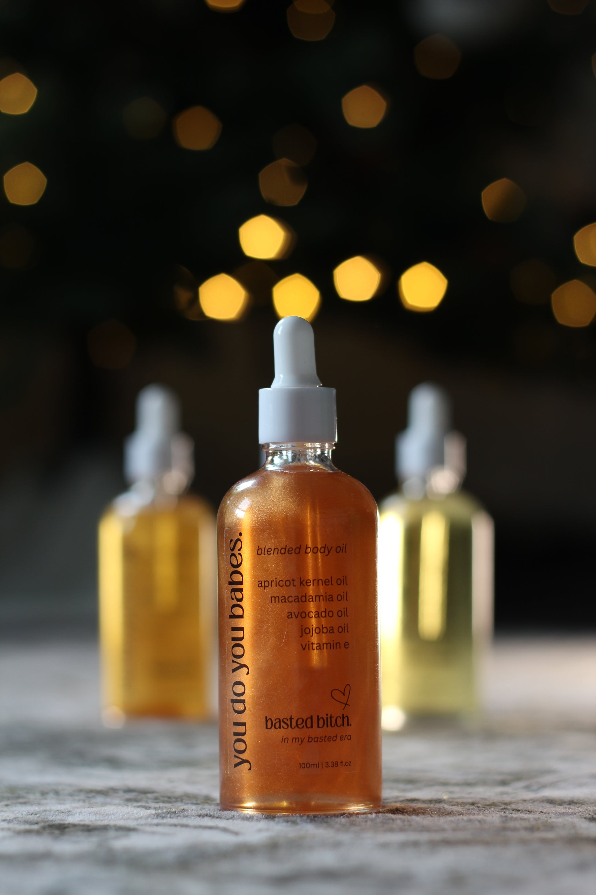 Bottles of 'you do you babes' Body Oil product with a blurred background
