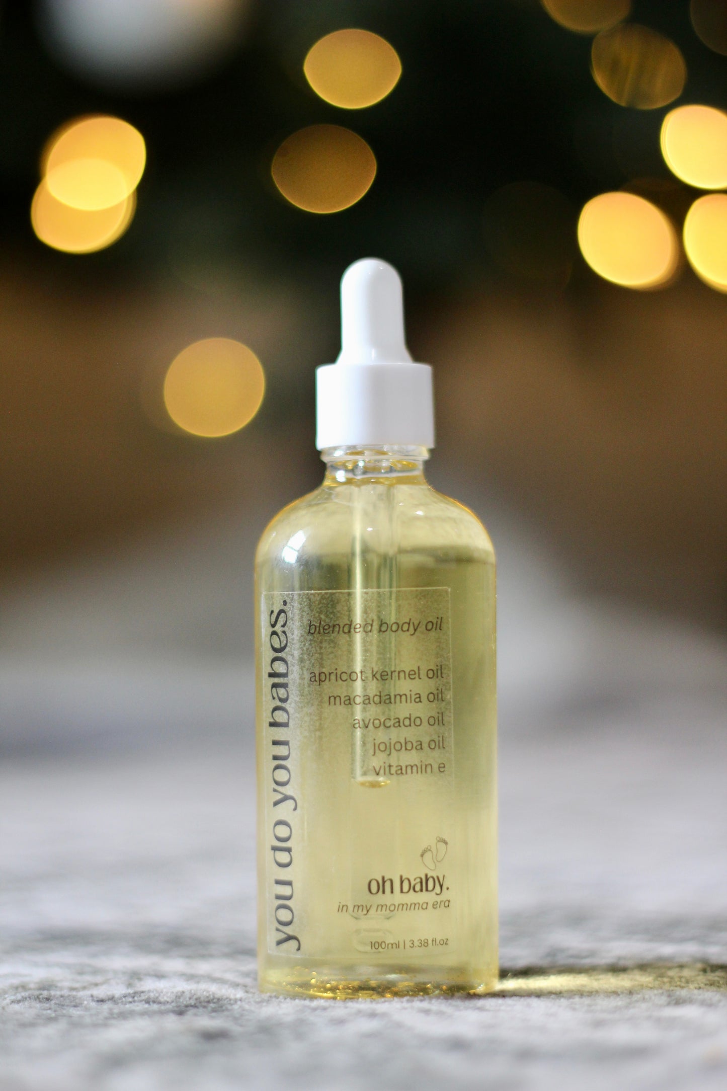 Bottle of 'you do you babes' Oh Baby body oil with a dropper on a blurred background