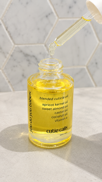 Glass bottle of cuticle oil with dropper on a marble surface