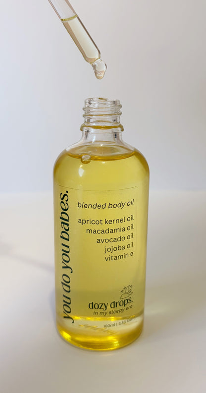 Bottle of blended body oil with a dropper on a white background