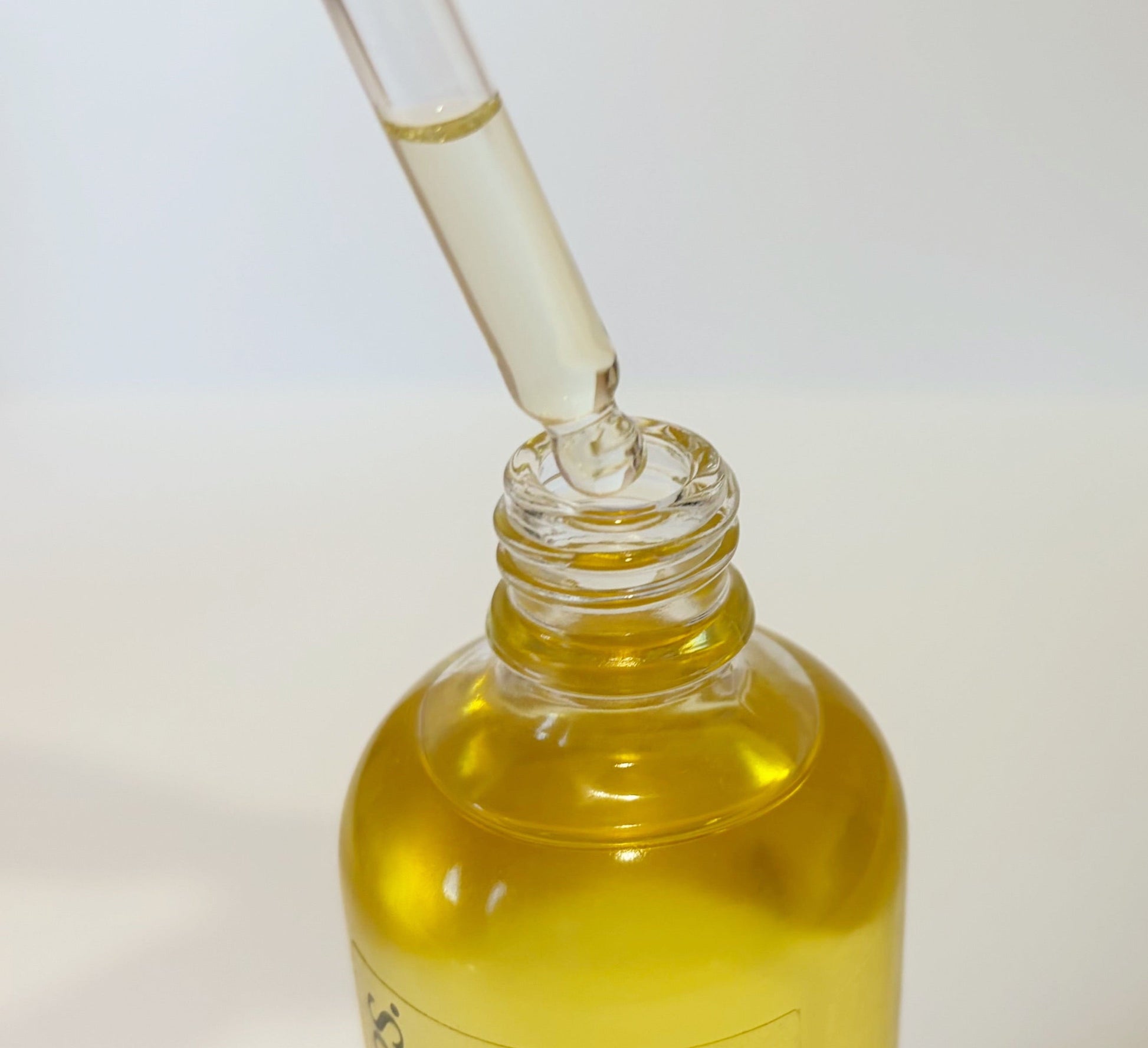 Bottle of blended body oil with a dropper on a white background