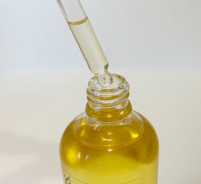 Bottle of blended body oil with a dropper on a white background