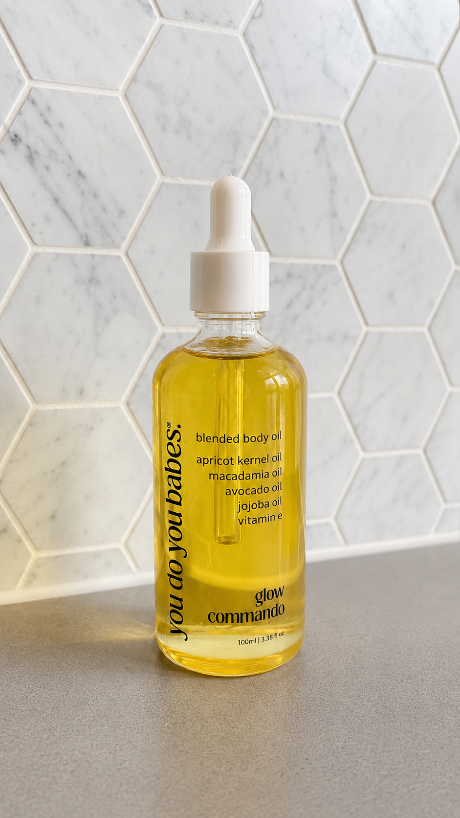 Bottle of blended body oil with a dropper on a marble surface