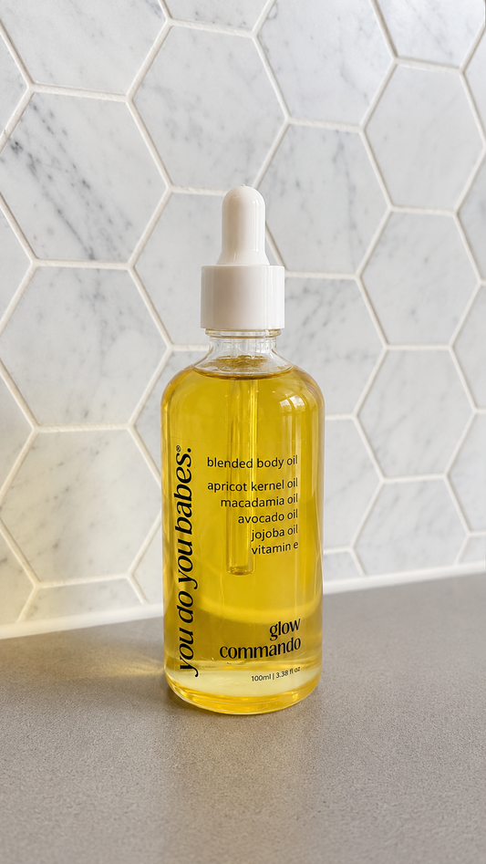 Bottle of blended body oil with a dropper on a marble surface