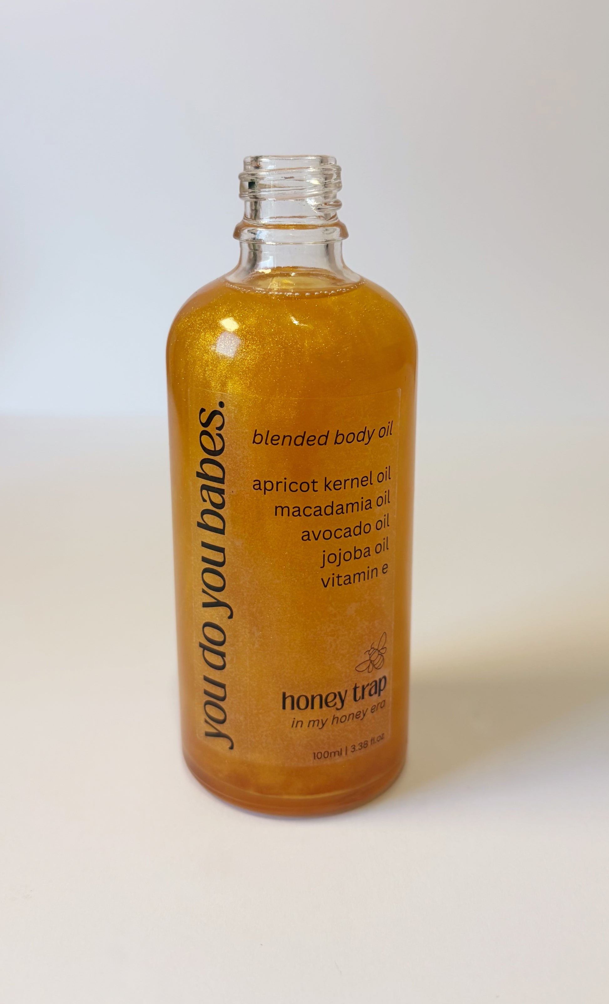 Bottle of 'you do you babes' honey trap blended body oil on a white background