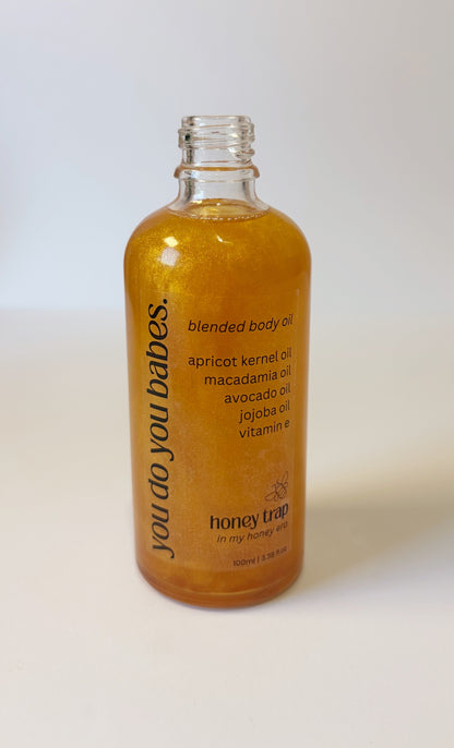 Bottle of 'you do you babes' honey trap blended body oil on a white background