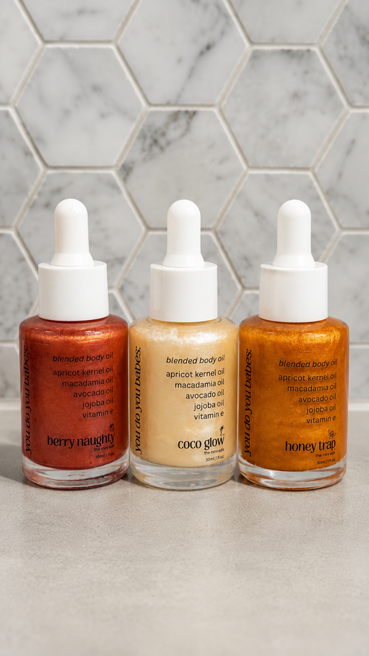 Three dropper bottles of different scents body oils on a marble surface with a hexagonal tile pattern.