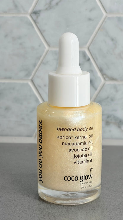 Bottle of Coco Glow blended body oil with a dropper on a grey surface.