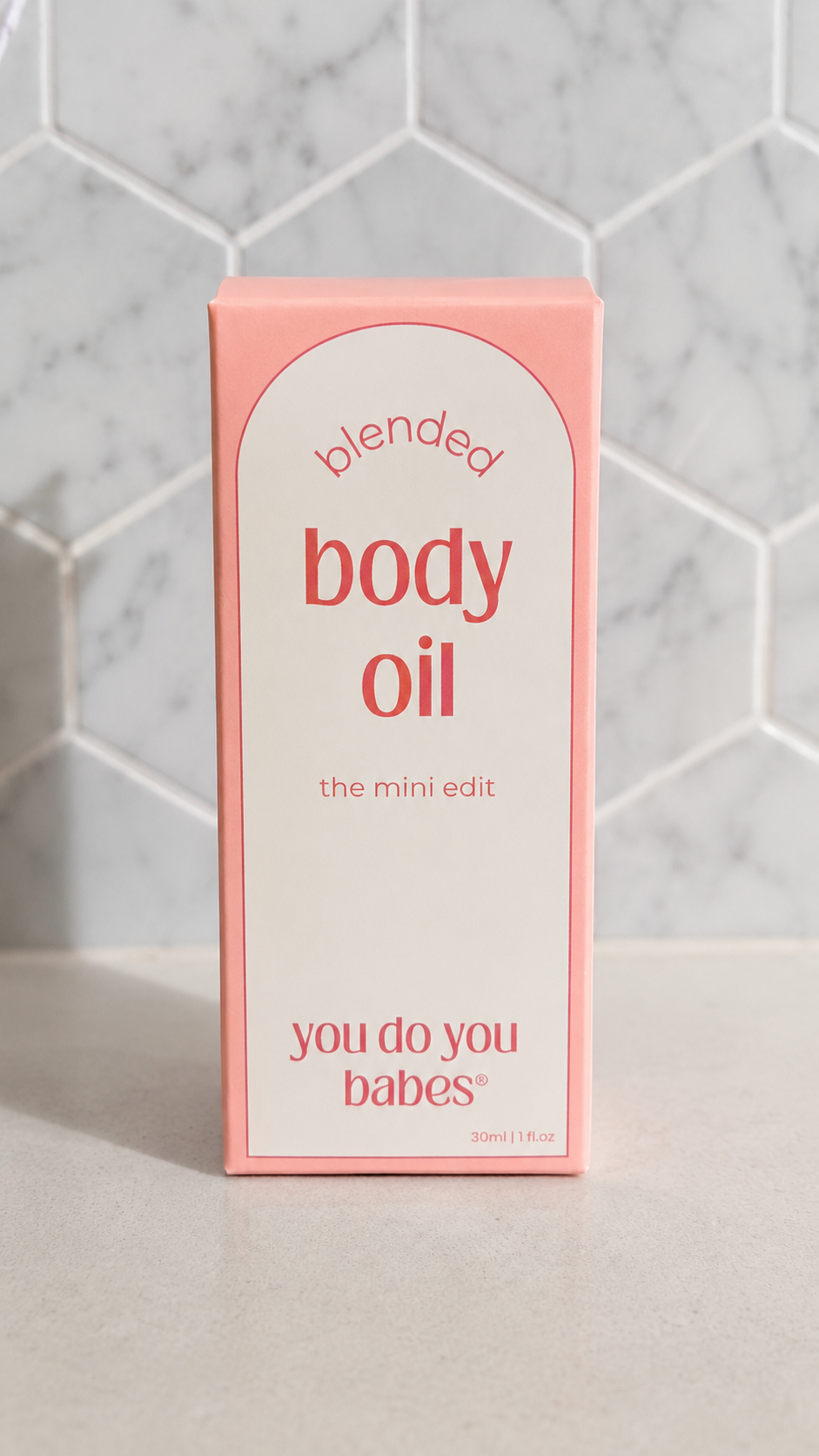 Box of 'blended body oil' with 'you do you babes' branding on a tiled wall background