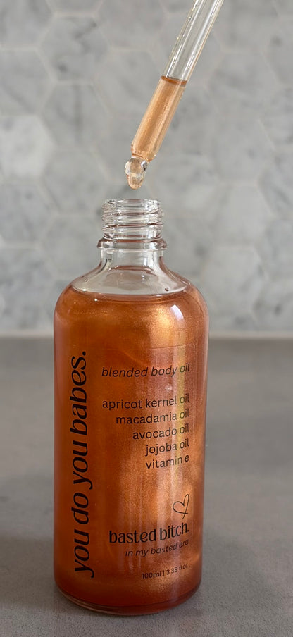 Bottle of blended basted bitch body oil with dropper on a gray background