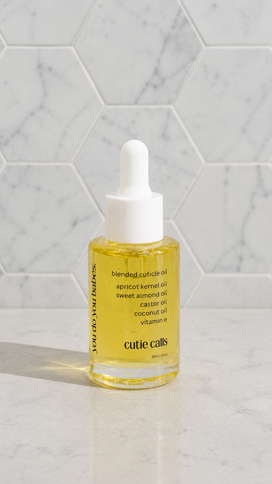 Bottle of cutie calls cuticle oil on a marble surface from you do you babes 