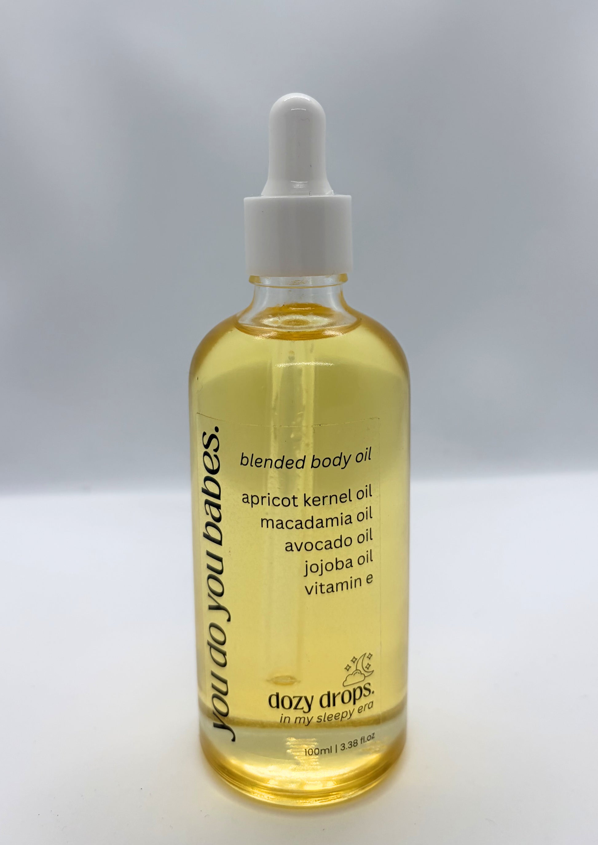 Bottle of dozy drops blended body oil with a dropper on a gray background
