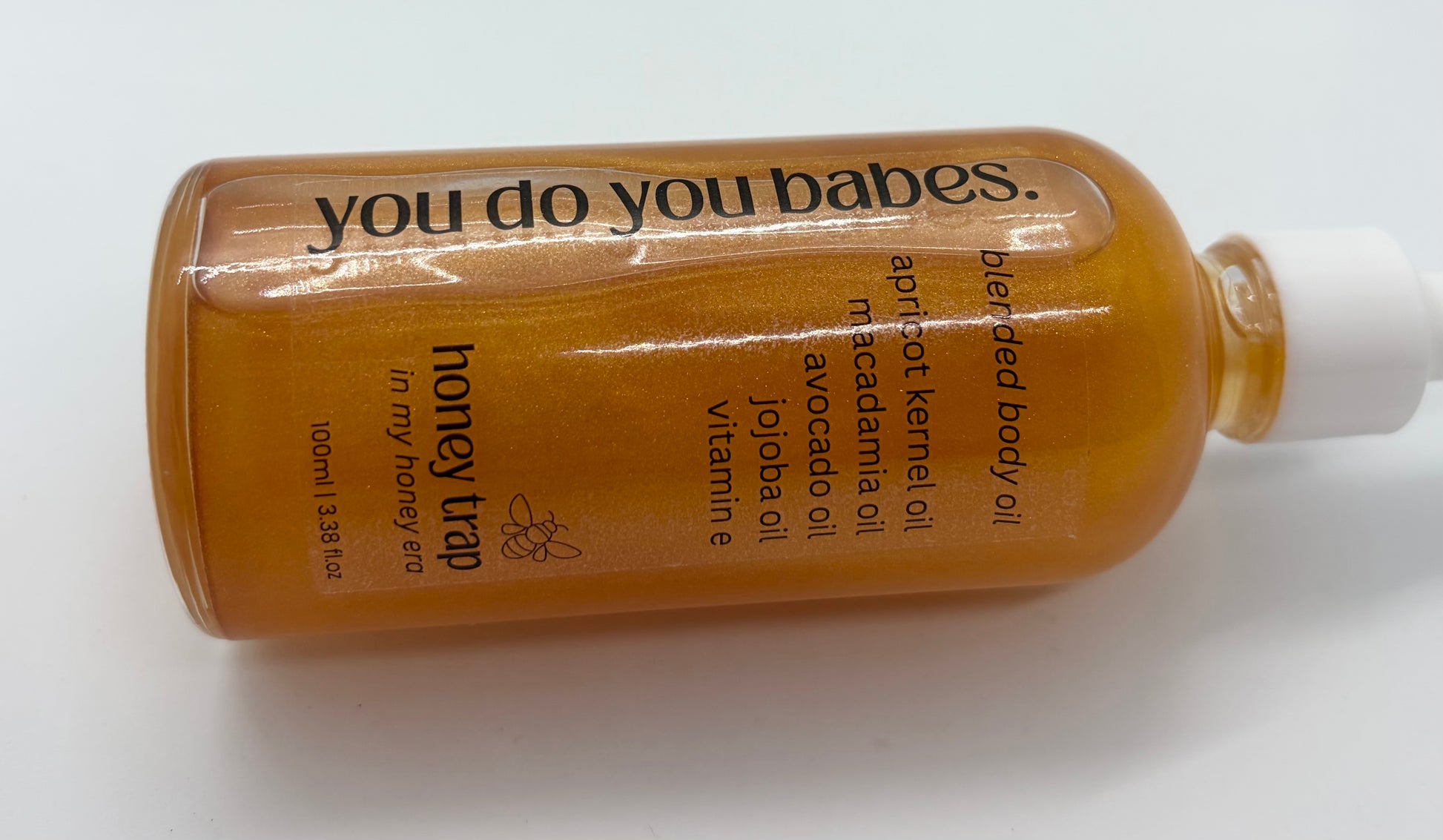 Honey trap body oil bottle with 'you do you babes' branding on a white background