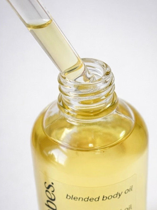 Bottle of blended body oil with a dropper on a white background