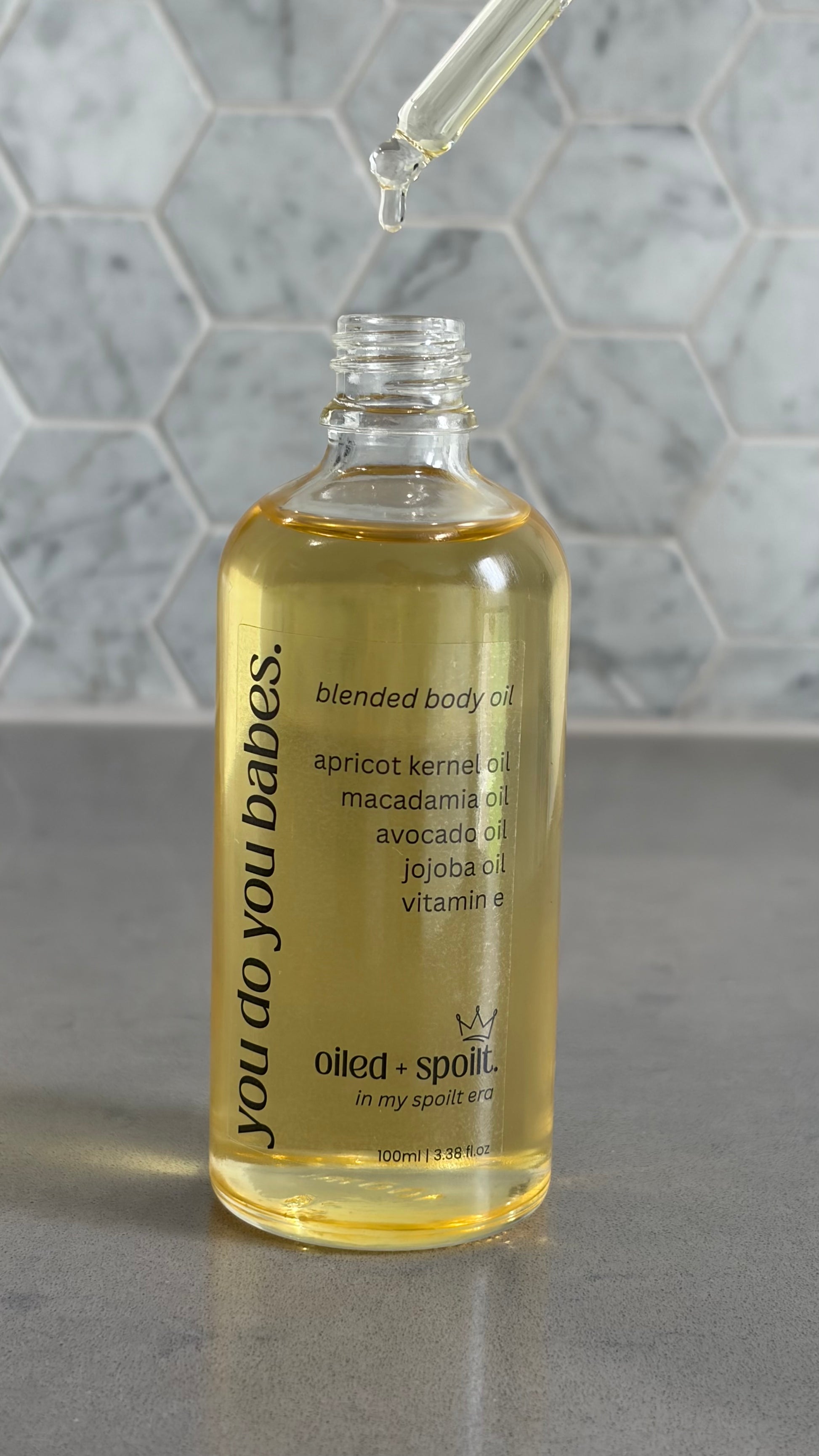 Bottle of blended body oil with dropper on a gray surface and marble background