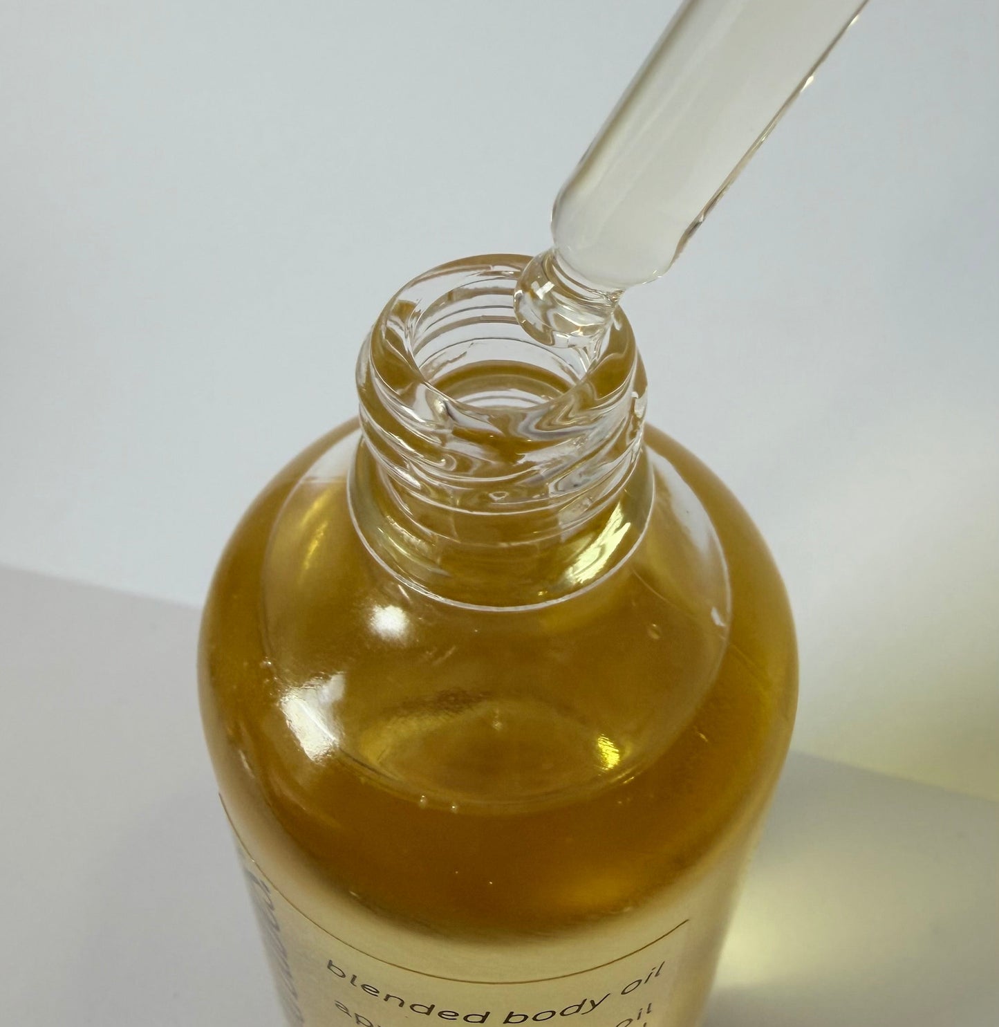 Glass bottle with dropper containing oil on a white background
